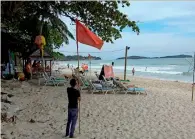  ?? AP ?? A man raises a red flag indicating rough weather conditions at Chaweng beach in Koh Samui, Thailand, on Thursday. —
