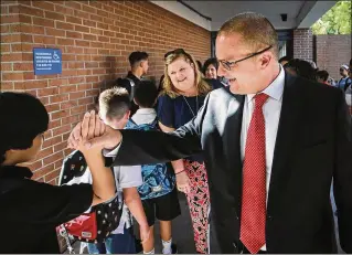  ?? BRUCE R. BENNETT / THE PALM BEACH POST ?? On the first day of school Monday in Palm Beach County, Deputy Superinten­dent/Chief of Schools Keith Oswald (right) greets students during a visit to Omni Middle School in Boca Raton as principal Allison Castellano (center) looks on.