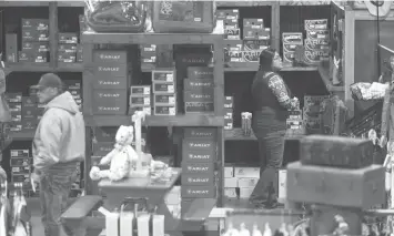  ?? William Luther/Houston Chronicle via AP ?? ■ Cadillac Jack’s Boot City manager Jacki Zapata, right, takes advantage of a slow moment in the Karnes City store to organize shelves of boots.