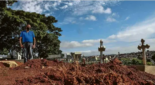  ?? Fotos Karime Xavier/Folhapress ?? Reinaldo Moraes, 52, observa o túmulo do filho, Gabriel Rogério, morto aos 20 em baile funk em Paraisópol­is há um ano