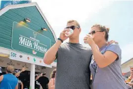  ?? WISCONSIN STATE FAIR ?? A couple enjoys cups of flavored milk at the state fair in Wisconsin, America’s Dairyland. The stand sells milk for 50 cents a cup.