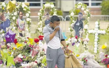  ?? Eric Gay Associated Press ?? A MAN delivers flowers and candles to a memorial for the victims of the school shooting in Uvalde, Texas.