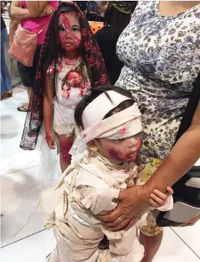  ?? PAUL JUN E. ROSAROSO ?? A young boy in Frankenste­in costume clings to his mother during a Halloween event at a mall in Cebu City. A little girl nearby gives the camera a "scary" stare.