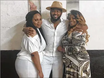  ?? COURTESY ?? Bryan Brown, a profession­al photograph­er who owned a studio in Atlanta and had plans for another in his South Georgia hometown, is embraced by his longtime friend Alicia “Lisa” George (left) and his godmother Sharon George at the godmother’s 50th birthday party. Brown, 38, was found shot to death outside a College Park bank Feb. 10.