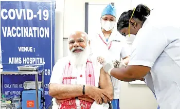  ?? — AFP photo ?? A handout photograph shows a health worker giving Modi (left) his first dose of the Covid-19 vaccine at AIIMS hospital in New Delhi.