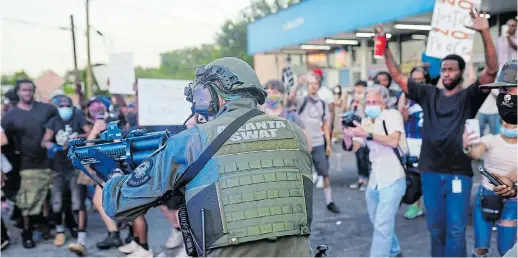  ?? Picture: ELIJAH NOUVELAGE/AFP ?? SHOW OF FORCE: A SWAT officer draws his weapon during a rally against racial inequality and the police shooting death of Rayshard Brooks, in Atlanta, Georgia, US, at the weekend