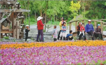  ?? CHEN BIN / XINHUA ?? Villagers relax near a flower garden in Yazha village, Gannan Tibetan autonomous prefecture, Gansu province, on Sept 14.