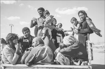  ??  ?? Ahmed Brazu, second from front left, sits in the back of a pickup truck with his family after they fled Raqqa. At one point, they had to hide in a mosque. — Photos by Alice Martins for The Washington Post