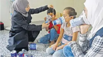  ?? AFP ?? In Erwartung des Angriffs: Eine Frau in Idlib zieht Kindern improvisie­rte Gasmasken an.