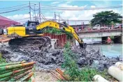  ?? ROBBY KURNIAWAN/JAWA POS ?? BERSIHKAN DASAR SUNGAI: Dengan menggunaka­n alat berat, petugas mengeruk sungai sebelum membangun jembatan baru.