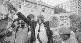  ??  ?? Zimbabwean­s celebrate Robert Mugabe’s resignatio­n on Tuesday outside the Parliament building in downtown Harare.