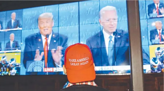  ?? Picture: Angus Mordant ?? A person wearing a "Make America Great Again" hat watches US President Donald Trump and Democratic rival Joe Biden tangle in the US presidenti­al debate in Nashville.