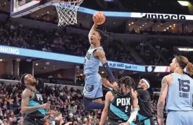  ?? BRANDON DILL/AP ?? Memphis Grizzlies guard Ja Morant (12) goes up for a dunk over Portland Trail Blazers forward Trendon Watford (2) in the second half of an NBA basketball game on Feb. 1 in Memphis.