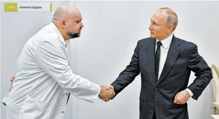  ?? ALEXEI DRUZHININ/SPUTNIK ?? Russian President Vladimir Putin, right, shakes hands with hospital chief Denis Protsenko while visiting COVID-19 patients in March in Kommunarka, Russia.