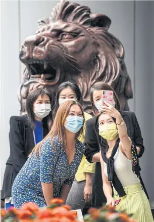  ?? AFP ?? People pose for a photo next to a lion statue outside HSBC Holdings Plc’s main office in Hong Kong yesterday.