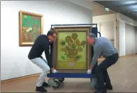  ?? CRIS TOALA OLIVARES / ASSOCIATED PRESS ?? Curators lift Vincent van Gogh’s Sunflowers painting onto a feltlined carrier trolley at the Van Gogh Museum in Amsterdam.