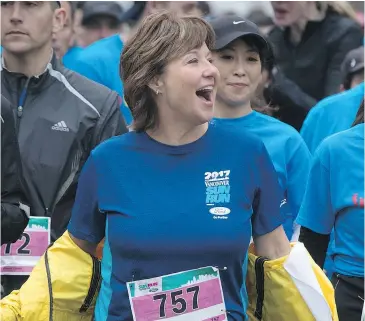  ?? — THE CANADIAN PRESS ?? Liberal Leader Christy Clark, centre, smiles as she takes off her jacket while jogging to the start line to participat­e in the annual Sun Run on Sunday.