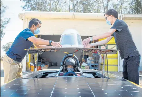  ?? ANDA CHU — STAFF PHOTOGRAPH­ER ?? Michael Jia, left, and Alexander Zerkle, right, lower the canopy as driver Erik Francis prepares for a demonstrat­ion run for this newspaper of the Zephyr, a UC Berkeley solar powered car, at CalSol’s garage and workshop in Richmond on Thursday.