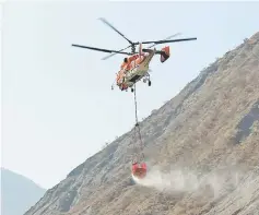  ?? — Reuters photo ?? A helicopter carries water in a bucket to extinguish forest fire in Muli county, in Liangshan Yi Autonomous Prefecture, Sichuan province, China.