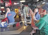 ?? JIM WEBER/THE COMMERCIAL APPEAL ?? Paige Edgar (right) and Dennis Belski follow news developmen­ts about the weekend’s mass shootings in Orlando, Fla., on television as they talk to bartender Dan Miller (left) at LGBT-friendly Dru’s Place on Madison in Midtown on Monday.