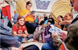  ?? [PHOTO BY STEVE SISNEY, THE OKLAHOMAN] ?? Celest Wisniewski, 10, plays cards with her brother Corbyn, 6, beside her mother, Noel, under the fourth-floor rotunda as teachers participat­e in a walkout at the Oklahoma State Capitol building on Thursday in Oklahoma City. Noel Wisniewski is a...