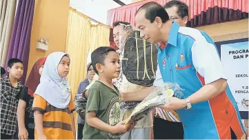  ??  ?? Mohammad Nazer presenting school bags to students of Sekolah Kebangsaan Haji Salleh Masri. — Bernama photo