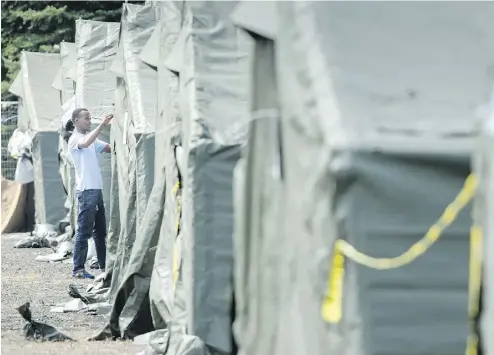  ?? PAUL CHIASSON / THE CANADIAN PRESS ?? An asylum seeker readjusts his tent in a temporary camp near Saint-Bernard-de-Lacolle, Que., earlier this month. The camp was set up to cope with the crush of asylum seekers crossing into Canada from the United States.