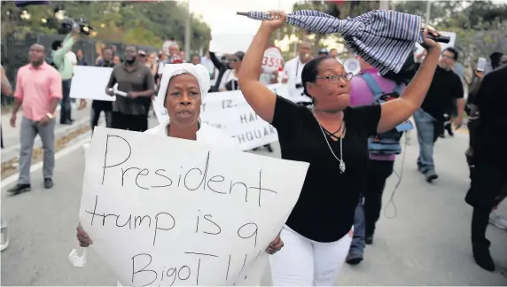  ??  ?? Jocelyne Pierre and Yanick Gorneo join a march in Miami, Florida, to mark the eighth anniversar­y of the massive earthquake in Haiti and to condemn Donald Trump’s reported statement about immigrants from Haiti, Africa and El Salvador