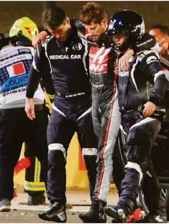  ?? Foto: afp ?? Betreuer stützen Formel-1-fahrer Romain Grosjean nach dessen Unfall in Bahrain. Der Franzose war mit hohem Tempo von der Strecke abgekommen. Sein Wagen fing sofort Feuer.
Europa League Gruppenpha­se, 5. Spieltag, u.a.
2. Bundesliga
3. Liga