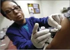  ??  ?? Ana Martinez, a medical assistant at the Sea Mar Community Health Center, gives a patient a flu shot Thursday in Seattle. AP PHOTO/TED S. WARREN