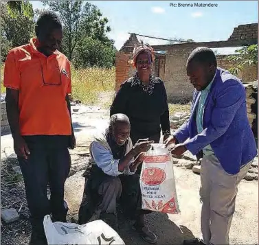  ??  ?? Gweru ward 4 councillor Martin Chivhoko (right) hands over a food hamper to an elderly person in his area recently. The councillor distribute­d food handouts to over 100 widows and the less privileged affected by the lockdown. Looking on (left) is Alderman Kenneth Sithole and an unidentifi­ed woman.