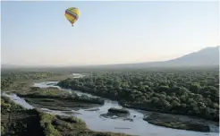  ??  ?? A hot-air balloon glides over the waters of the Rio Grande River and its forested shores near Albuquerqu­e, N.M.