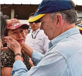  ??  ?? Colombian President Juan Manuel Santos comforting a resident in Mocoa on Saturday.