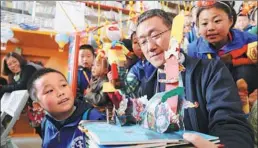  ?? PHOTOS PROVIDED TO CHINA DAILY ?? Yan Hongbing, the paper-art designer of the book, with children at a promotiona­l event in Xi’an.