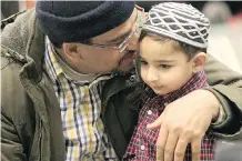  ?? JIM WELLS ?? A father cuddles his son as they attend services at the Genesis Centre in northeast Calgary on Friday.