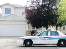  ??  ?? Police guard a house in Calgary on Tuesday, after taking a suspect into custody. Dustin Duthie, 25, faces three counts of second-degree murder.