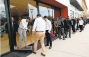  ?? GARY REYES/STAFF ?? Tesla Motors employees open doors for more than 300 customers who queued up Thursday morning to order Model 3 sedans at the Stanford Shopping Center in Palo Alto. Fans also lined up in Walnut Creek and Dublin.