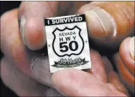  ??  ?? Wayne Cameron of the White Pine County Chamber of Commerce shows a lapel pin given to motorists who “survive” a U.S. Highway 50 trek.