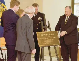  ?? BRIAN JEFFRIES/CAPITAL GAZETTE ?? Secretary of the Navy Carlos Del Toro, right, and Capt. Greg Mendenhall reveal the Carter Hall placard to the family of former President Jimmy Carter during a renaming ceremony Friday.