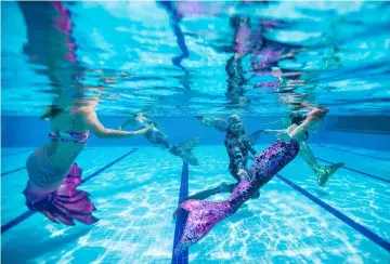  ??  ?? Diver Lee Boon Leong (centre) watches swimmers perform wearing mermaid tails in a swimming pool in Klang. — AFP photos