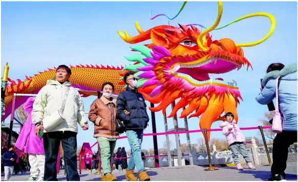  ?? AP ?? People walk by a giant dragon lantern decorated near the frozen Houhai Lake in Beijing yesterday. Chinese shares rose yesterday as investors appeared to welcome Beijing’s choice of an industry veteran to replace its top securities watchdog in its latest effort to boost confidence in ailing markets.