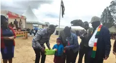  ?? ?? Minister of Public Service and Social Welfare, Professor Paul Mavima (left) handsover sunscreen lotions to a child living with albinism at Nerutanga Primary School in Buhera West last week on Wednesday. — Picture By Ray Bande