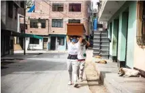  ?? – AFP photos ?? Workers carry a coffin made of Mapresa (pressed wood) to be stored at a factory at Juan de Lurigancho district in Lima.