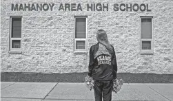  ?? DANNA SINGER/AP ?? Brandi Levy wears her former cheerleadi­ng outfit while standing outside Mahanoy Area High School in Mahanoy City, Pa., on April 4.