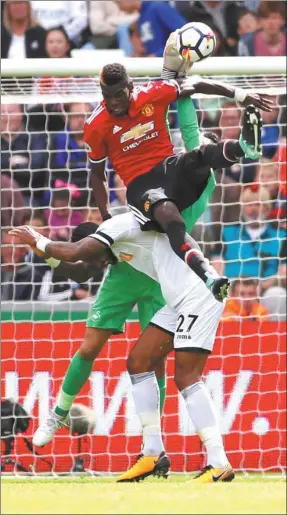  ?? ANDREW BOYERS / ACTION IMAGES VIA REUTERS ?? Manchester United’s Paul Pogba clatters into Swansea City’s Kyle Bartley and goalkeeper Lukasz Fabianski during their Premier League match in Wales on Saturday. Pogba netted United’s third goal as it kicked off the season with back-to-back 4-0 wins.
