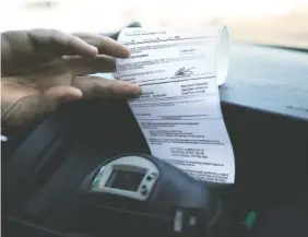  ??  ?? Left: Mullinix prints a traffic citation from a machine in his patrol car Friday while on traffic patrol.