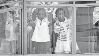  ?? Ben Curtis / Associated Press ?? Two Kenyan children on Saturday look out from an upper level in the reopened Westgate Shopping Mall in Nairobi, Kenya. Nearly two years ago, a terrorist attack there left at least 67 people dead after security forces battled four al-Qaida-linked gunmen...