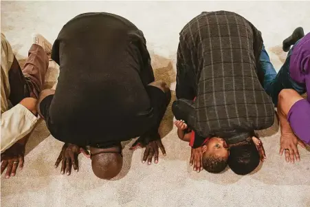  ?? Michael Ciaglo / Houston Chronicle ?? Baroque Ali, 3, looks over the shoulder of his father, Abdul Wahid Muhammad, during prayer before breaking fast during Ramadan last week at Masjid Warithud-deen Mohammed, Houston’s oldest mosque.