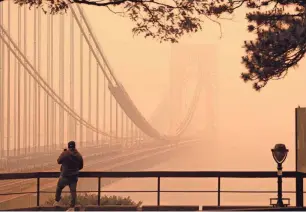  ?? SETH WENIG/AP ?? A man talks on his phone as he looks through the haze at the George Washington Bridge from Englewood Cliffs, N.J.