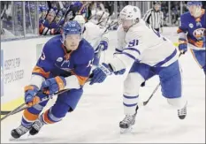  ?? Kathy Willens / Associated Press ?? Toronto’s John Tavares, right, the former Islanders captain, uses his stick to check current Islander Mathew Barzal.